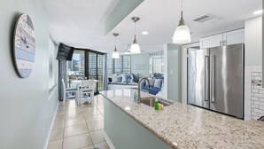 A modern kitchen with a marble countertop, stainless steel appliances, and pendant lighting. - Sunbird 612 East - Free Beach Chairs! (Panama City)