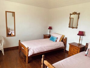 Ein Schlafzimmer mit einem hölzernen Bett, zwei Nachttischen inklusive Lampen, einem Spiegel und einem Sessel.