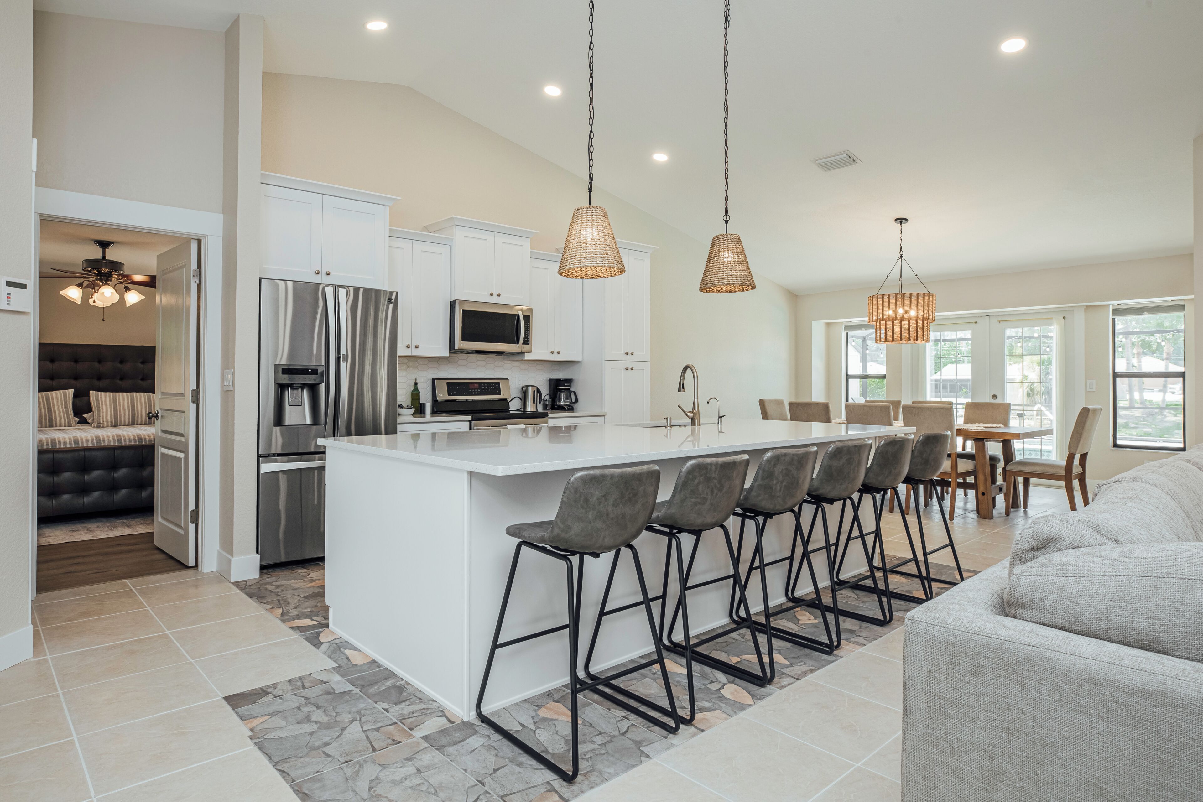 A modern kitchen with a central island, bar stools, and pendant lighting.