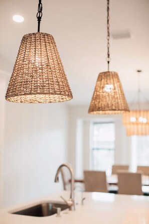 A modern kitchen with pendant lighting, a sink, and a dining area in the background. - The Gulf Access Oasis Heated Pool & SPA, Ramp/Dock (Port Charlotte)