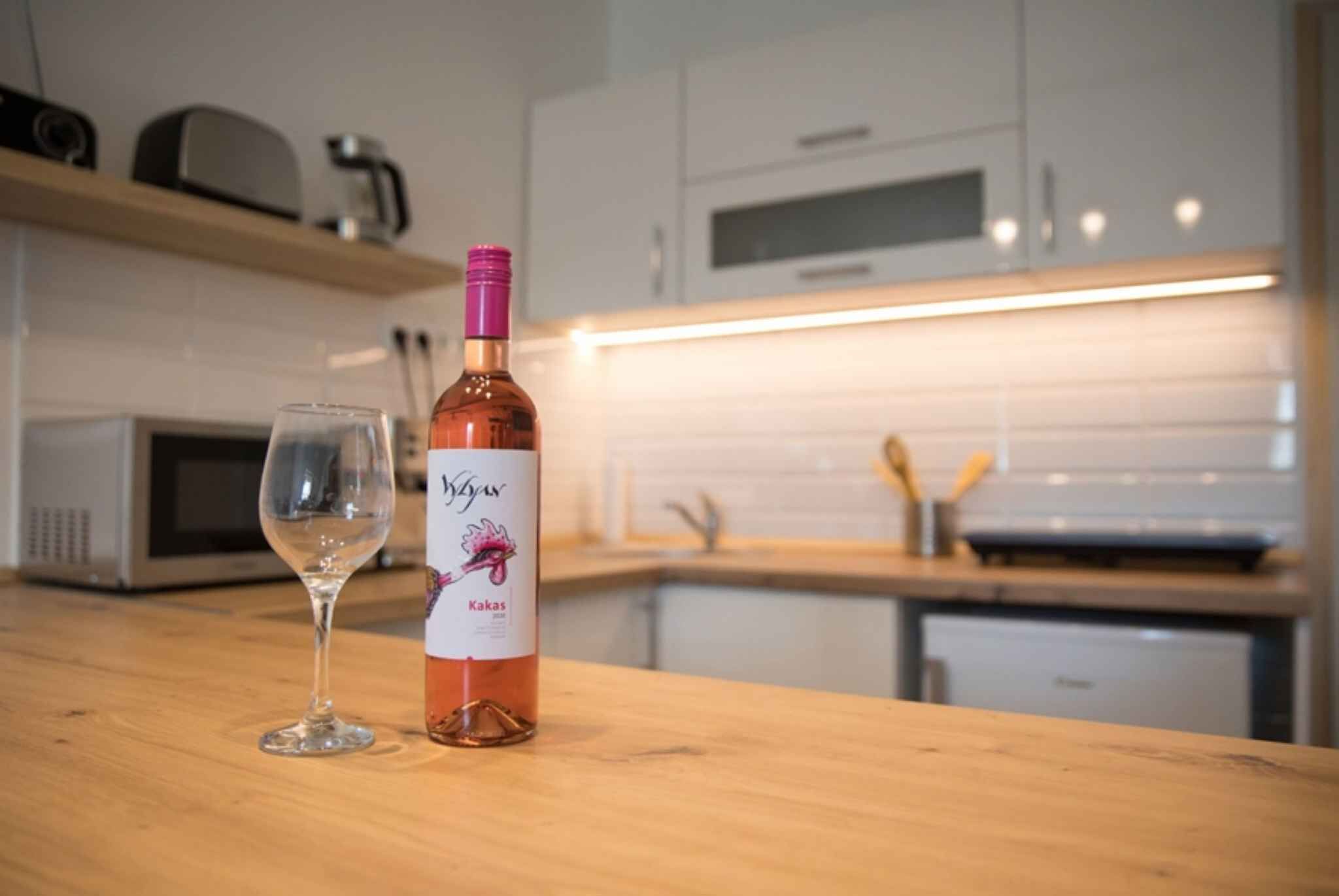 Una botella de vino y una copa sobre la encimera de la cocina.