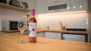 A bottle of wine and a wine glass on a kitchen counter.