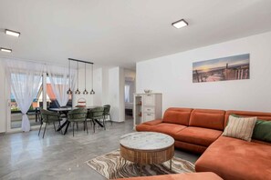 Un salon moderne avec un canapé, une table à manger, des chaises et un tableau accroché au mur.