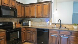 A kitchen with wooden cabinets, a microwave, stove, dishwasher, and a sink. - Peaceful 3-bedroom house in charming Stillwater for your getaway (Stillwater)