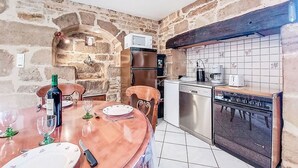 Une cuisine aux murs en pierre, avec une table à manger en bois et des appareils électroménagers modernes.