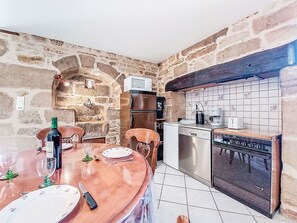 A kitchen with stone walls, a wooden dining table, and modern appliances.
