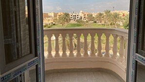 A balcony with a view of a residential area, including buildings and palm trees.