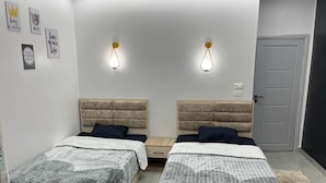 A room with two beds, a door, and wall decorations.