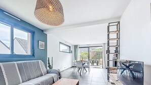 En moderne stue med sofa, sofabord og fjernsyn. Der er spiseplads med stole og bord.