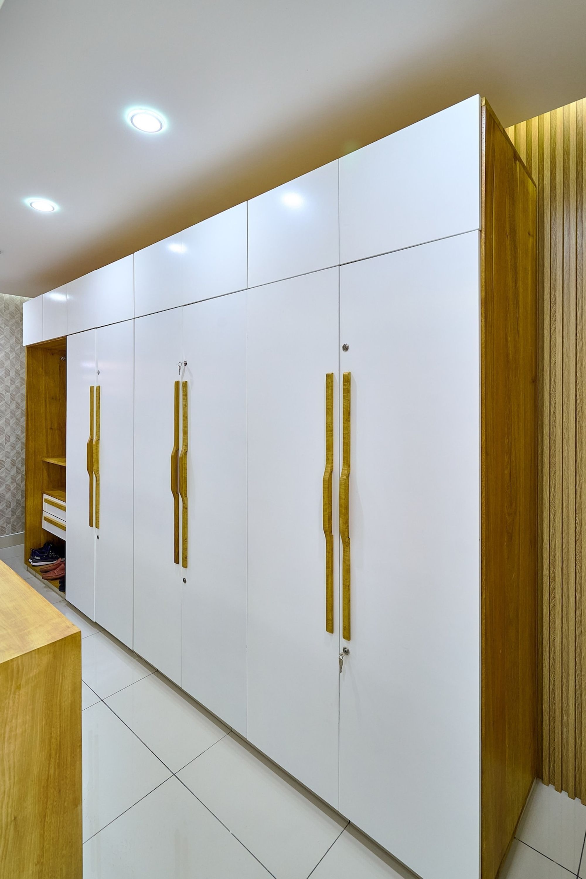 A modern room with white cabinets and wooden accents, a wooden desk, and a tiled floor.