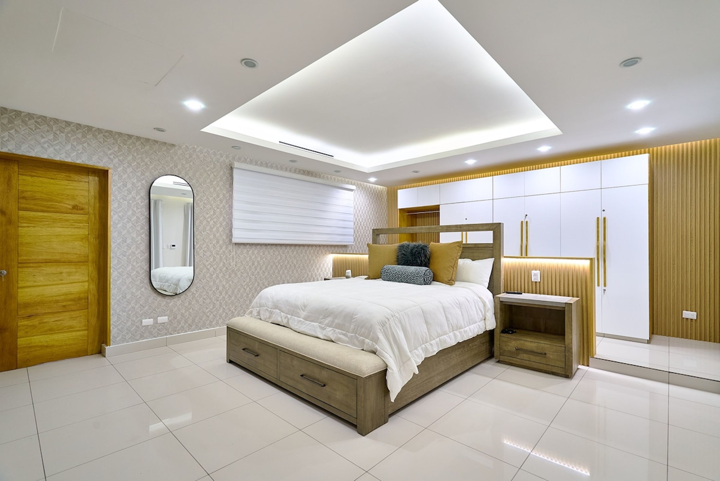 A modern bedroom with a bed, bedside tables, a wardrobe, and a mirror.