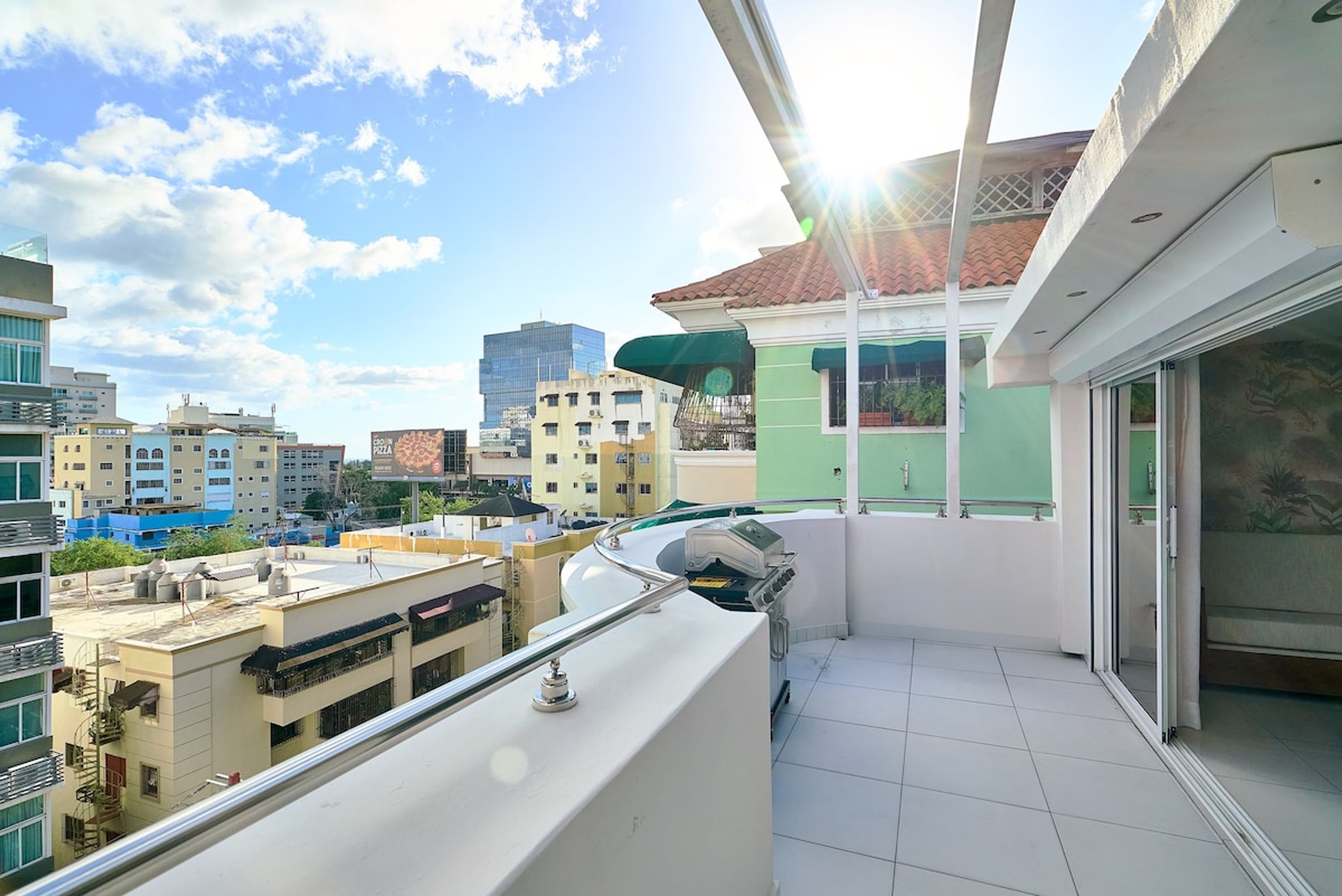 Un balcon offrant une vue sur le paysage urbain, avec des bâtiments et un ciel dégagé.