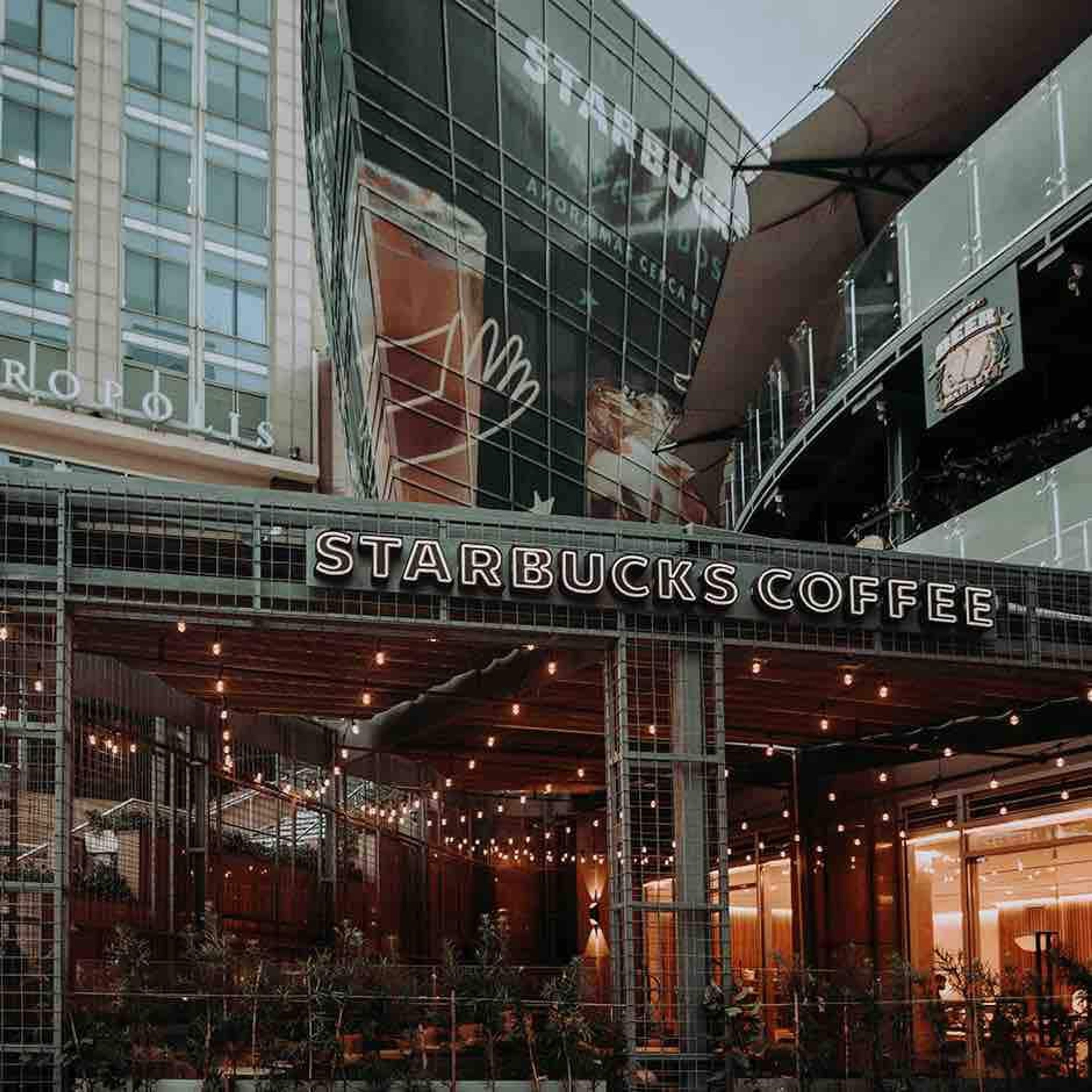 A Starbucks Coffee with a modern glass facade and outdoor seating area.