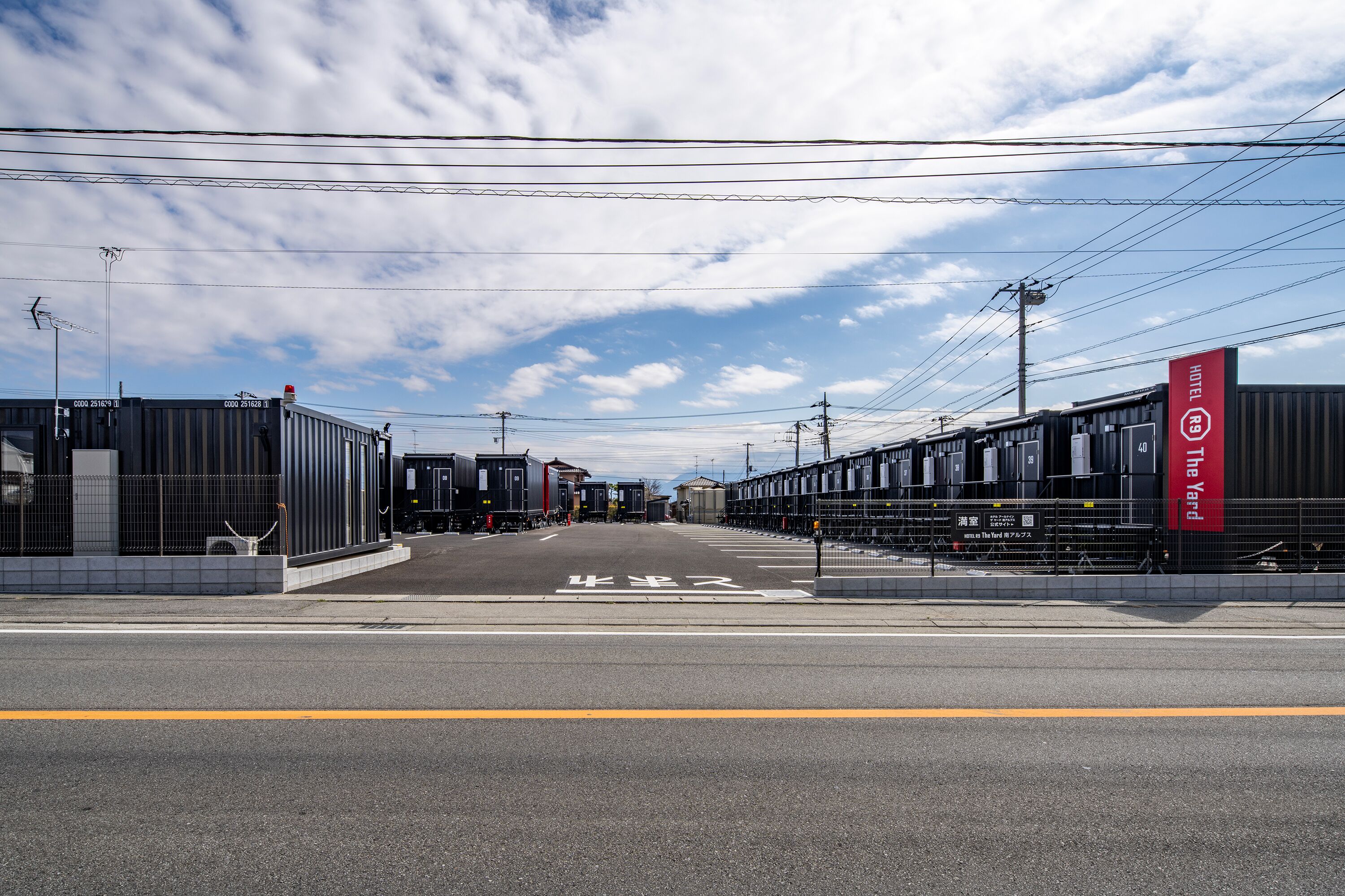 A street view with a hotel sign, a pedestrian crossing, and industrial buildings.