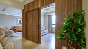 A modern interior with a sliding wooden partition, a sofa, a chair, and a potted plant. - 3BR Elegant Spot Downtownsd Family Pool (Santo Domingo)