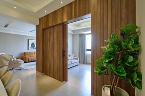 A modern interior with a sliding wooden partition, a sofa, a chair, and a potted plant. - 3BR Elegant Spot Downtownsd Family Pool (Santo Domingo)