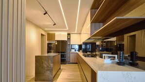 A modern kitchen with wooden cabinets, a marble island, and built-in appliances. - 3BR Elegant Spot Downtownsd Family Pool (Santo Domingo)