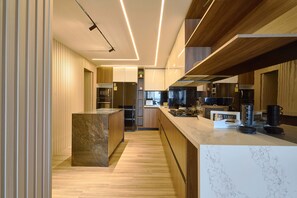 A modern kitchen with wooden cabinets, a marble island, and built-in appliances. - 3BR Elegant Spot Downtownsd Family Pool (Santo Domingo)