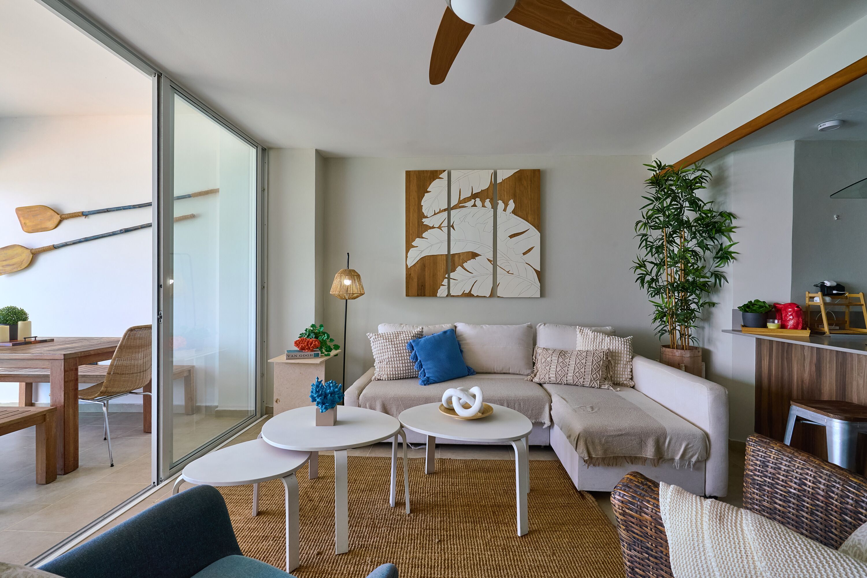 A modern living room with a sofa, two side tables, a ceiling fan, and a large window.