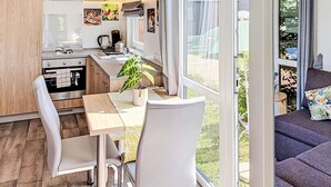 A modern kitchen with a dining area, large windows, and a view of the outdoors. - Tiny Haus Sigl by Interhome (Beilngries)
