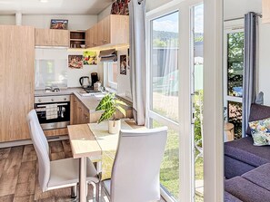 A modern kitchen with a dining area, large windows, and a view of the outdoors. - Tiny Haus Sigl by Interhome (Beilngries)
