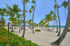 A beach with palm trees, lounge chairs, and a clear view of the ocean. - 3BR Hemingway Retreat Juandolio Walktobeach GYM (Guayacanes)