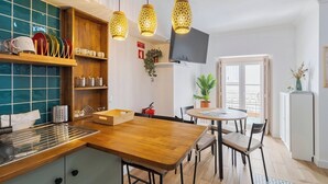 A modern kitchen with wooden countertops, a built-in stove, and hanging pendant lights. - Duplex Postigo da Pedra (Setúbal)