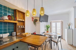 A modern kitchen with wooden countertops, a built-in stove, and hanging pendant lights. - Duplex Postigo da Pedra (Setúbal)