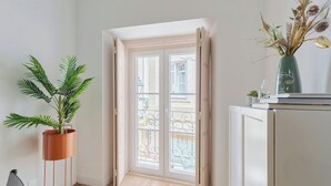 A room with a potted plant, a cabinet, and a balcony door. - Duplex Postigo da Pedra (Setúbal)