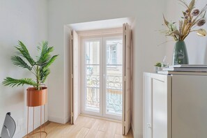 A room with a potted plant, a cabinet, and a balcony door. - Duplex Postigo da Pedra (Setúbal)