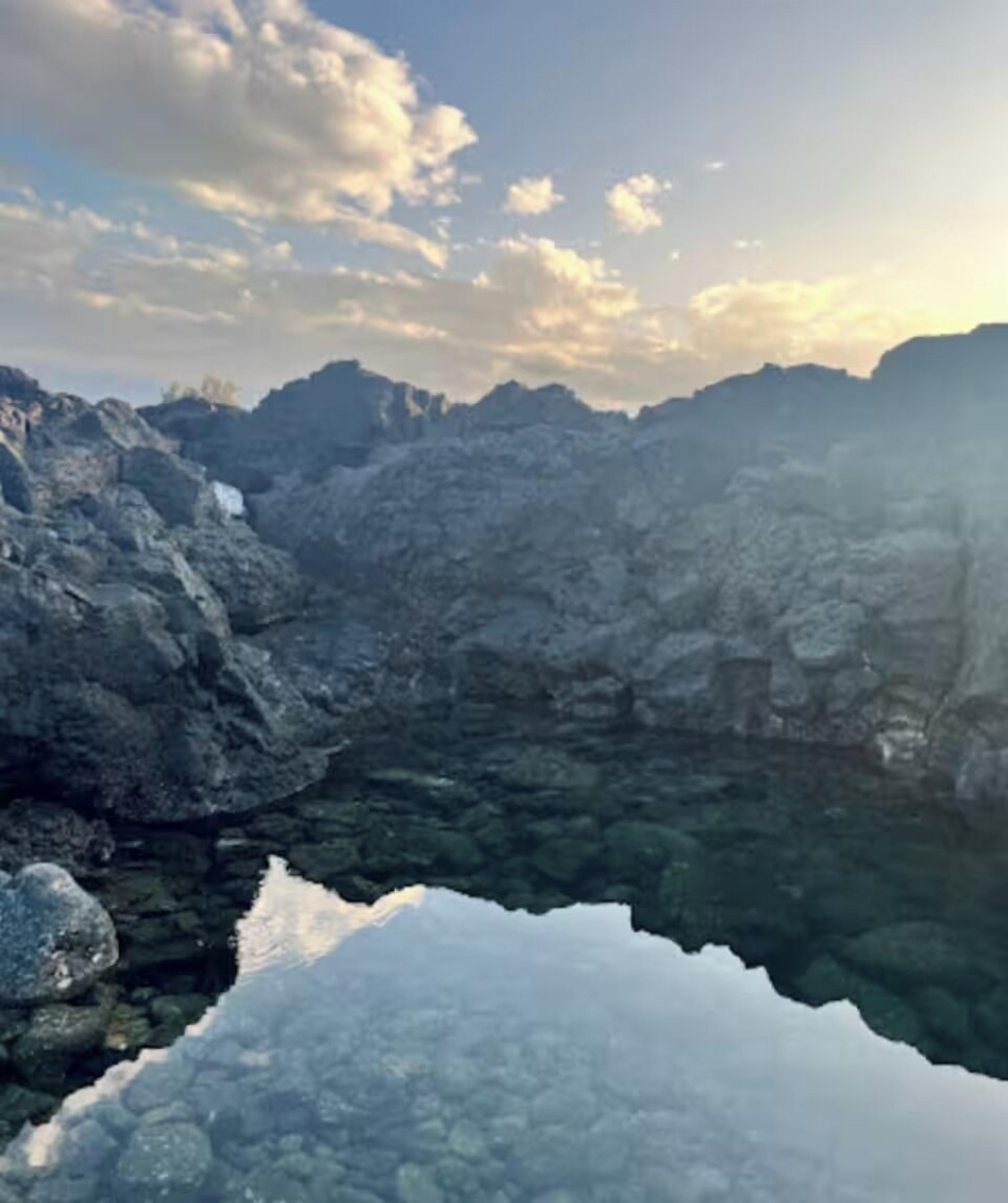 A mountainous landscape with a clear lake reflecting the sky.