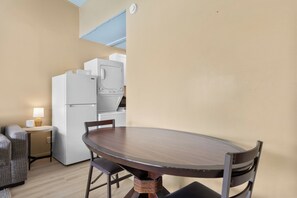 Eine kleine Küche mit Kühlschrank, Mikrowelle und Backofen. Es gibt einen Esstisch mit Stühlen und eine kleine Couch.