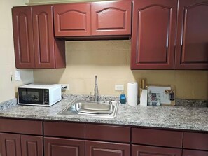 Una cocina equipada con microondas, lavaplatos y armarios.