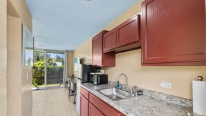 A kitchen with a large window, a sink, a refrigerator, and a microwave.
