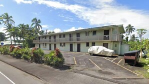A two-story motel with a covered parking area, surrounded by tropical vegetation.
