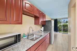 A kitchen with granite countertops, stainless steel appliances, and red cabinetry.