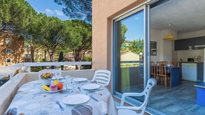 Un área de comedor al aire libre con una mesa para dos, vistas a la cocina y un balcón con barandilla.