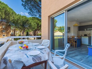 An outdoor dining area with a table set for two, a view of the kitchen, and a balcony with a railing. - Santa Barbara by Interhome (Cavalaire)