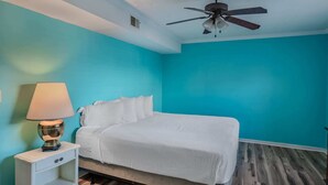 Une chambre à coucher avec un lit, une table de chevet, une lampe et un ventilateur de plafond.