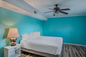 A bedroom with a bed, a nightstand, a lamp, and a ceiling fan.