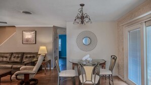 Un salon avec un canapé en cuir, une table de salle à manger ronde entourée de chaises, une lampe et un lustre.
