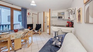 Un soggiorno con divano, un tavolo da pranzo con sedie, un caminetto, angolo cottura con forno a microonde e una finestra con tende.