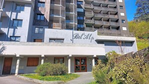 Un hotel a più piani dal design moderno, con balconi, ingresso coperto e un cartello con la scritta 'Bel Alp'.
