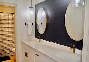 Une salle de bain avec deux lavabos, un grand miroir et un porte-serviettes.