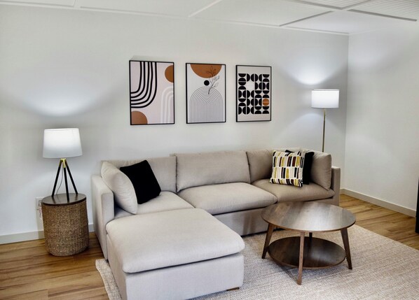 A modern living room with a sofa, ottoman, round coffee table, and two floor lamps.