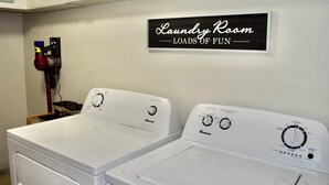 A laundry room with two white Amana washing machines, a water level dial, a wash temperature dial, and a sign that reads 'Laundry Room Loads of Fun.' - Fully Remodeled & Newly Furnished Browne's Addition Condo - Dog Friendly! (Spokane)