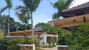 Une maison moderne avec un mur en pierre, une pergola en bois et un chemin menant à l’entrée.