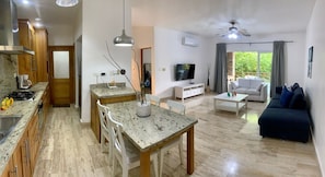 A modern kitchen with granite countertops, a dining area with a marble table, a living room with a sofa and a TV, and a ceiling fan. - Terrenas Beach Spot Monserrat Pool 5min Beach (Las Terrenas)