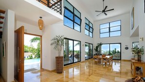 A spacious interior with a high ceiling, large windows, a dining area, and a view of the outdoors. - Beach Mountain Villa Terrenas Pool BBQ 6BR (Las Terrenas)