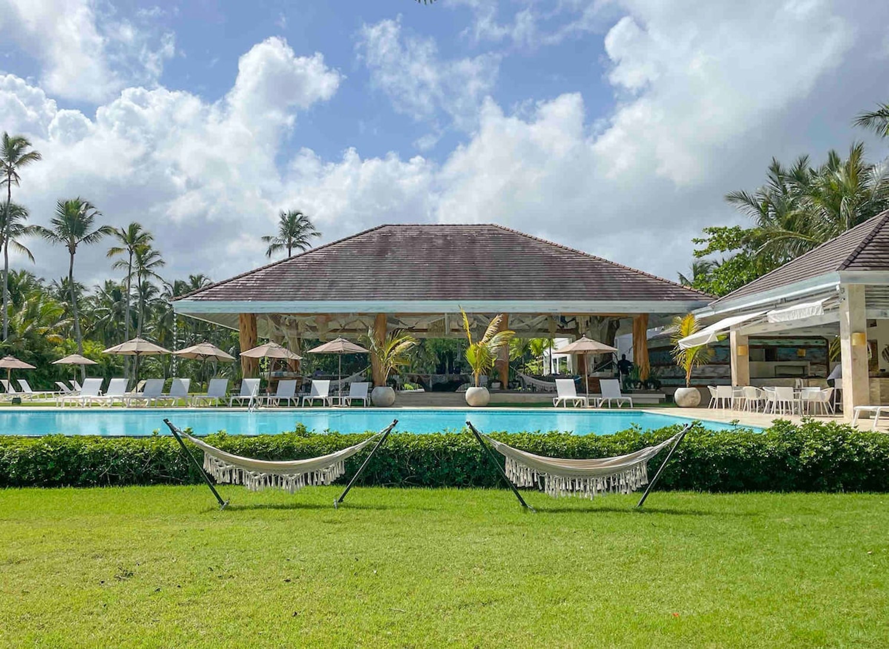 A pool area with lounge chairs, a covered seating area, and a hammock.